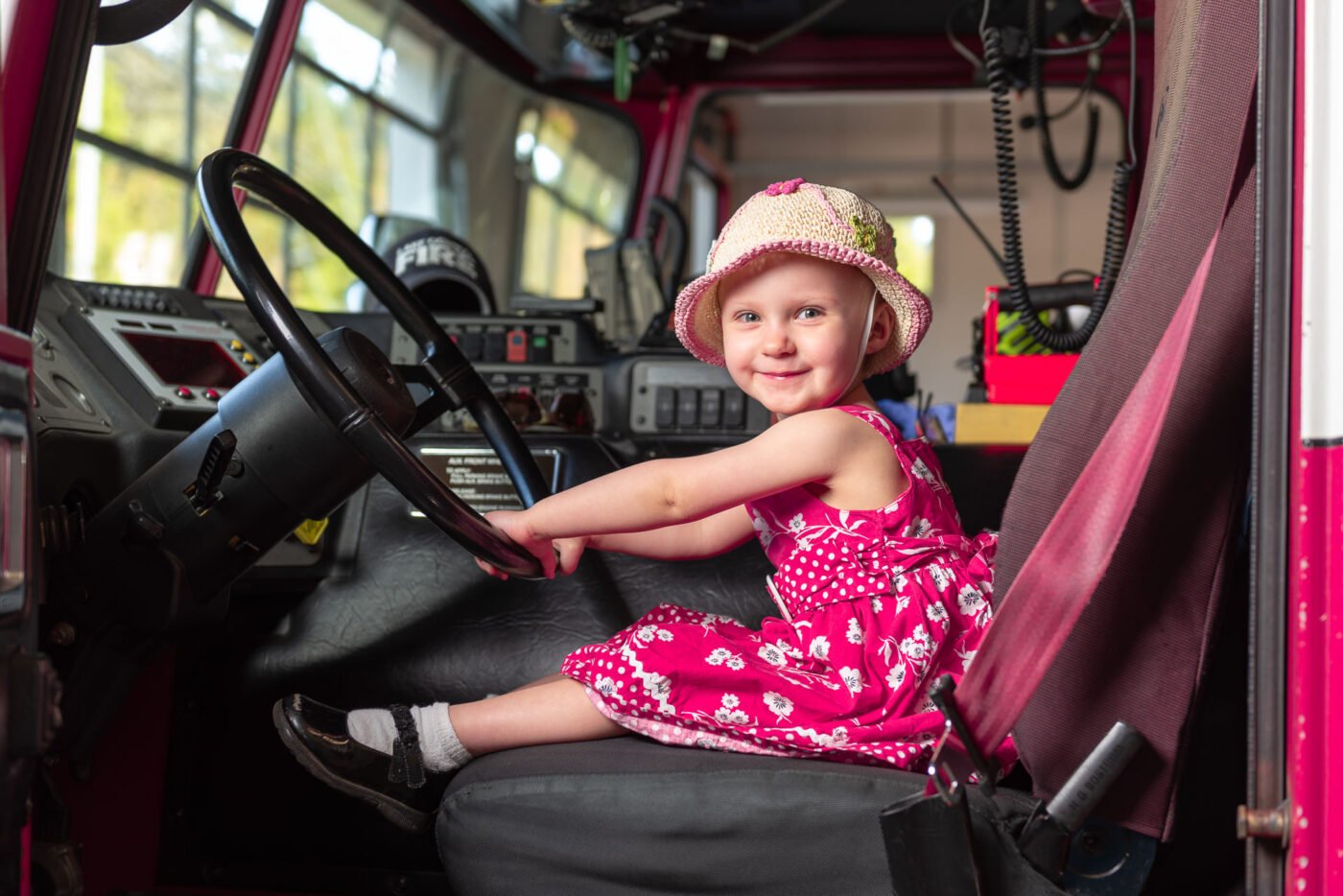 girl-sitting-in-fire-truck-smiling girl-sitting-in-fire-truck-smiling